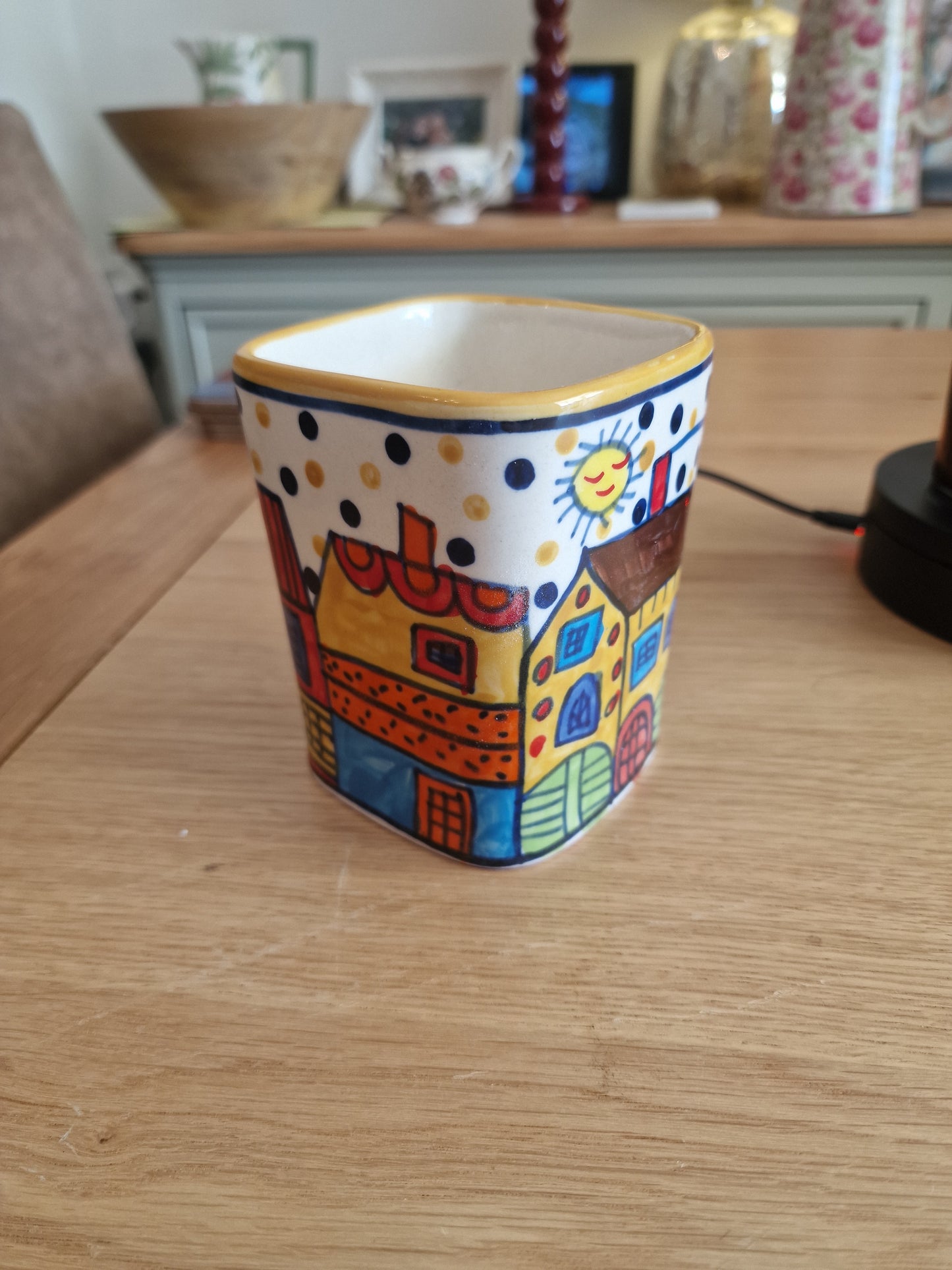 Pair of Colourful Whimsical Village Ceramic Pots H4.5" in colourful hand-painted ceramic with village scenes and polka dot border on a wooden table in Kitchen & Dining