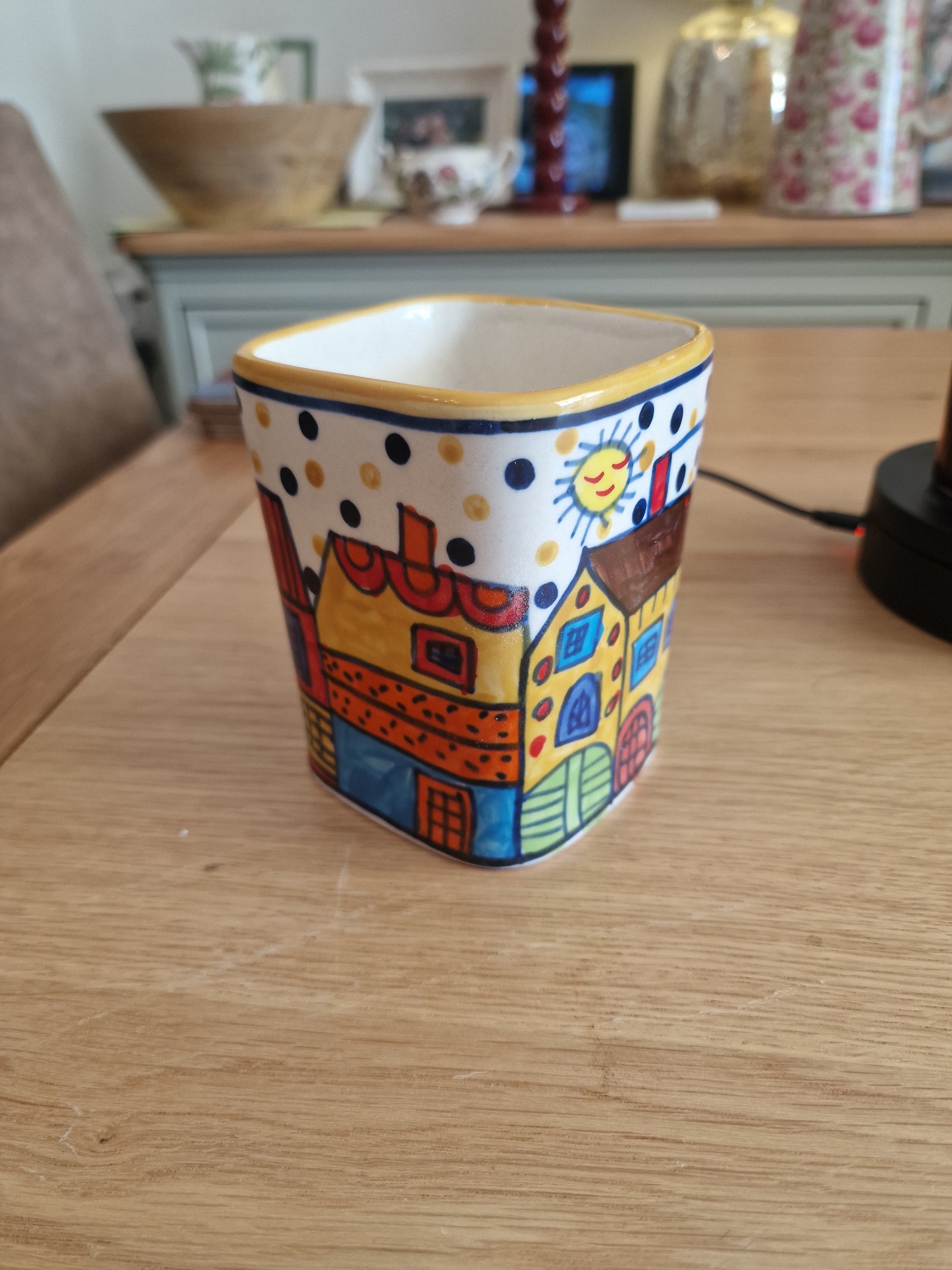 Pair of Colourful Whimsical Village Ceramic Pots H4.5" in colourful hand-painted ceramic with village scenes and polka dot border on a wooden table in Kitchen & Dining